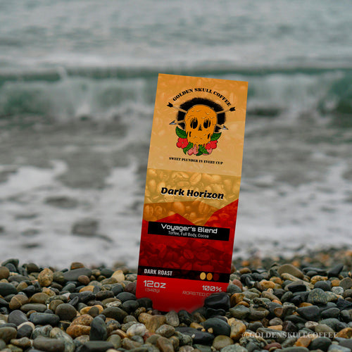 Coffee bag labeled Dark Horizon by Golden Skull Coffee on pebbles with a blurred natural background