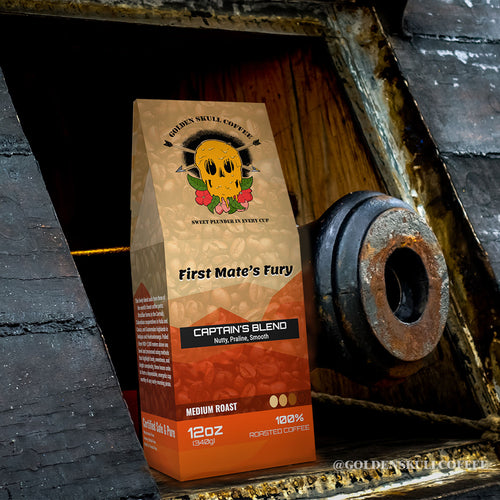 Coffee bag labeled 'First Mate's Fury' by Golden Skull Coffee next to a pirate cannon in a gun port.