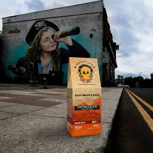 Coffee bag labeled 'First Mate's Fury' by 'Captain's Blend' on a sidewalk with a mural of a child holding a spyglass in the background.