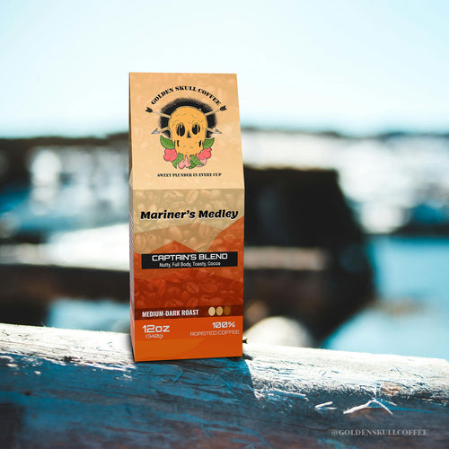 Coffee package labeled 'Mariner's Medley' by Golden Skull Coffee on a wooden surface with a blurred natural background.